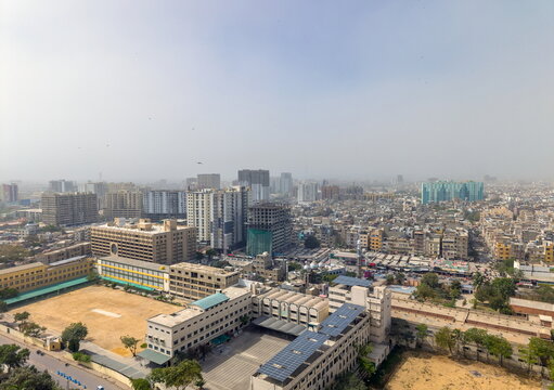 Aerial view of the dense urban cityscape featuring St. Patrick's Cathedral and surrounding residential buildings under a hazy sky in Karachi, Sindh, Pakistan.