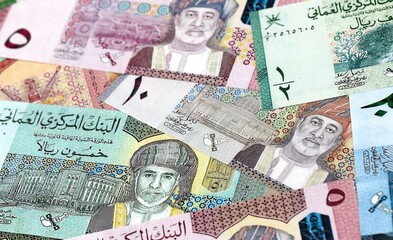 Obraz premium Omani rial money bills pile on table. Oman banknotes of OMR currency close up.
