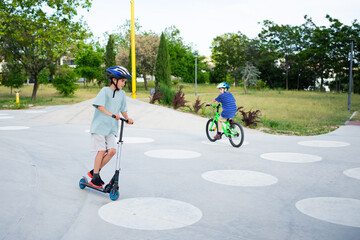 Children riding bicycle and scooter in traffic playground wearing helmets © Arianne