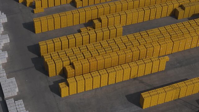 Drone footage captures vast outdoor storage of yellow building blocks, likely near the A1 autostrada in the Po Valley region of Italy