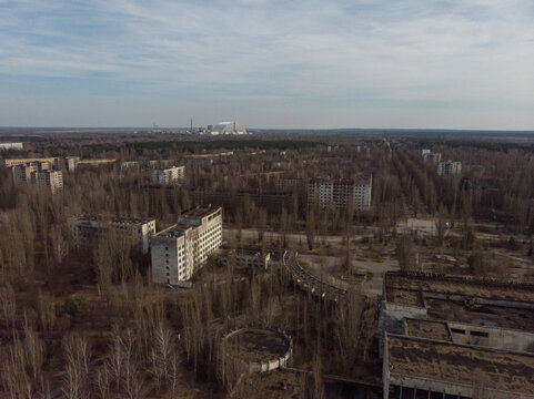 Aerial view of abandoned apartment blocks and overgrown streets with the Chernobyl nuclear power plant in the distance Pryp'yat', Kyiv Oblast, Ukraine.