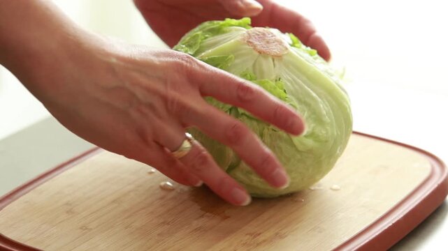 Fresh green iceberg lettuce on wooden cutting board, close up of healthy salad ingredient