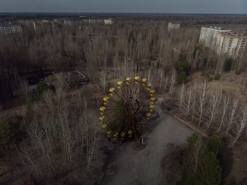 Aerial view of the abandoned Ferris wheel in the amusement park surrounded by overgrown trees and derelict buildings Pryp'yat', Kyiv Oblast, Ukraine.