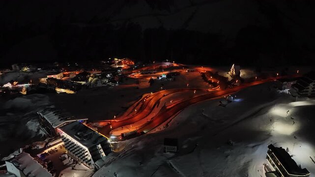 Night Drone view of Gudauri in Georgia town with snow covered mountains, ski slopes and town after fresh snowfall in winter season. Gudauri ski resort with fresh powder snow, Georgia.