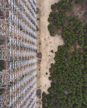 Aerial view of the massive Duga radar station steel lattice structure next to a dense pine forest in Prypyat, Kyiv Oblast, Ukraine.