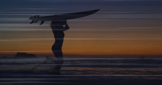 Sports surfer holding board aloft walking wet sand as sunset signaling end banding reflections