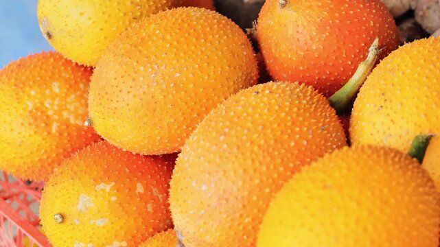 Macro shot of spiky gac fruit skin glowing in warm tropical daylight market