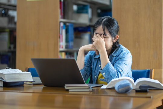 Student struggles with stress during study session at library focused on overcoming challenges in academic environment