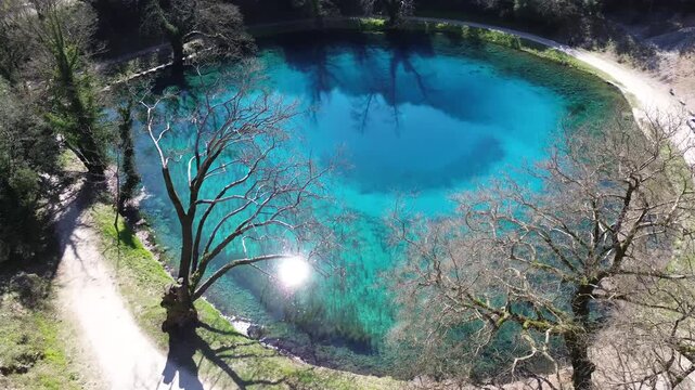 Cinematic high-angle drone shot of the Louros river springs. Panoramic view showing the unique circular blue lake formation and the limestone geology of Epirus, Greece. Ideal for science and nature.