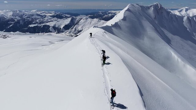 Freeride skiers climbing and descending Bidara peak in Gudauri on deep fresh powder snow, winter adventure in Georgia mountains. Backcountry freeride and skiing untouched powder in snowy mountains.
