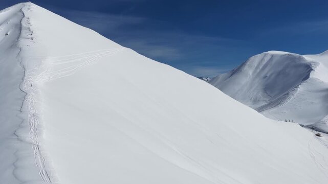 Freeride skiers climbing and descending Bidara peak in Gudauri on deep fresh powder snow, winter adventure in Georgia mountains. Backcountry freeride and skiing untouched powder in snowy mountains.