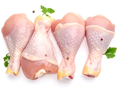 Four raw chicken drumsticks with parsley on a white background