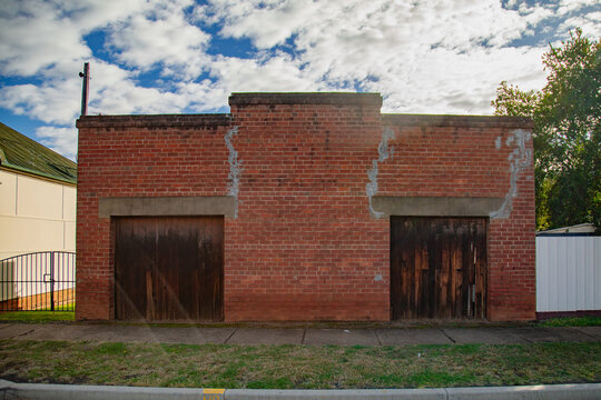 Old brick building with weathered wooden doors and a cloudy sky overhead