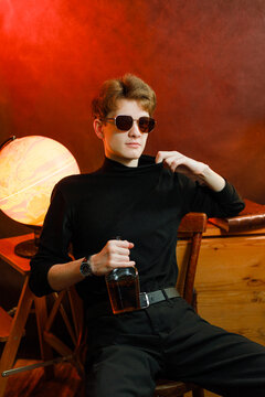 Confident young man in black turtleneck holding whiskey bottle.