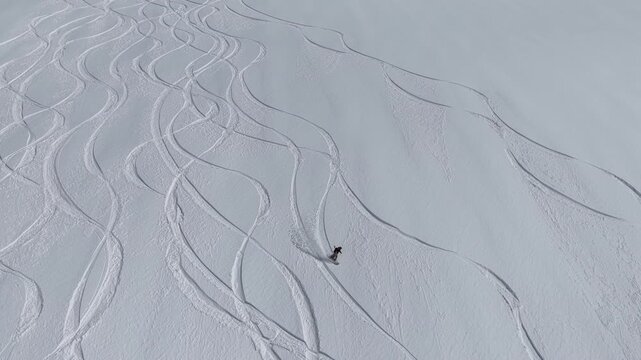 Freeride skiers climbing and descending Bidara peak in Gudauri on deep fresh powder snow, winter adventure in Georgia mountains. Backcountry freeride and skiing untouched powder in snowy mountains.