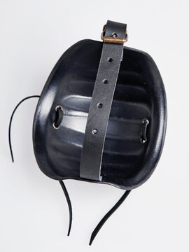 Top view of a black molded shoulder armor piece with a leather strap and lacing displayed on a white background.