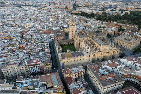 Aerial view of the Seville Cathedral and Giralda tower surrounded by historic rooftops and the urban skyline in Seville, Andalusia, Spain.