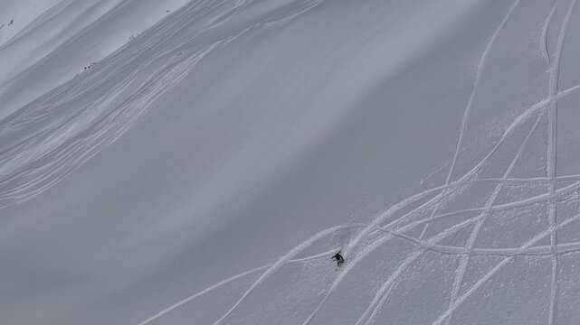 Freeride skiers climbing and descending Bidara peak in Gudauri on deep fresh powder snow, winter adventure in Georgia mountains. Backcountry freeride and skiing untouched powder in snowy mountains.