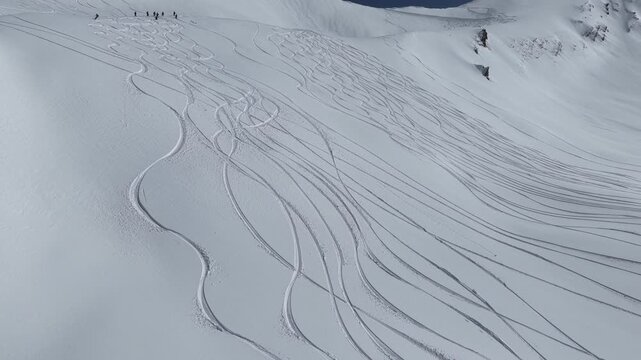 Freeride skiers climbing and descending Bidara peak in Gudauri on deep fresh powder snow, winter adventure in Georgia mountains. Backcountry freeride and skiing untouched powder in snowy mountains.