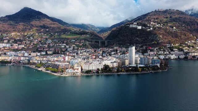 Aerial view of the cityscape featuring Montreux's buildings and water reflecting the sky, nestled between mountains and lake, Vaud, Switzerland.
