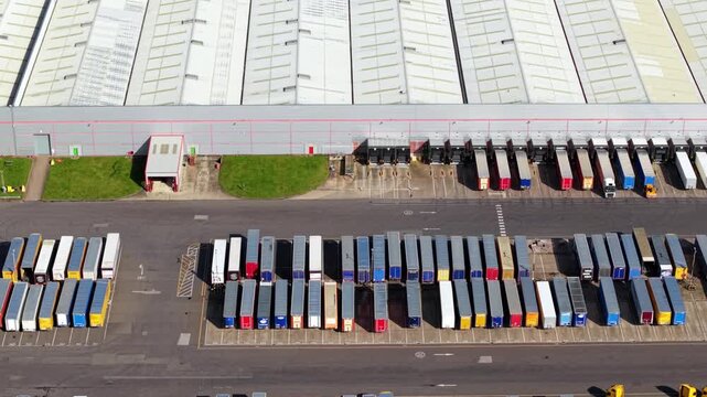 Aerial view of many trucks in rows showing a uniform pattern of colors and shapes, with a large warehouse in the background, Worksop, England, United Kingdom.