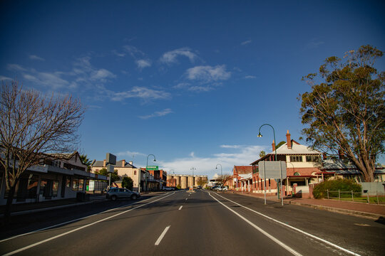 Empty Australian country town main street with historic buildings and silos under a clear blue sky