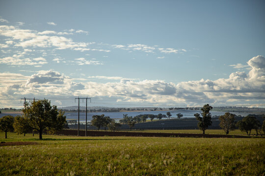 Vast solar farm stretches across rolling hills under a dramatic cloudy sky