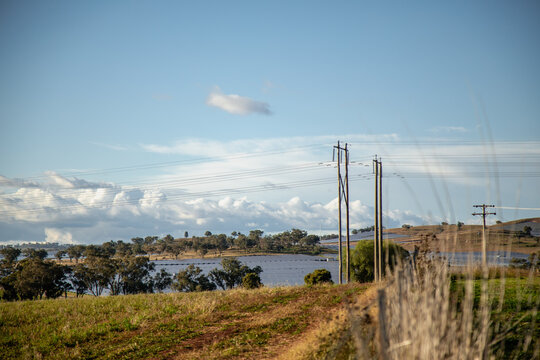 Rural landscape with solar panels and power lines under a cloudy sky