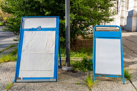 Two blank blue portable advertising a-frame sandwich board signs on a city sidewalk
