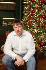 Man sitting in a chair in front of a decorated Christmas tree