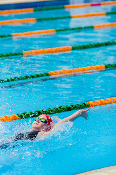 Girl racing/ training competitive backstroke at a public swimming pool