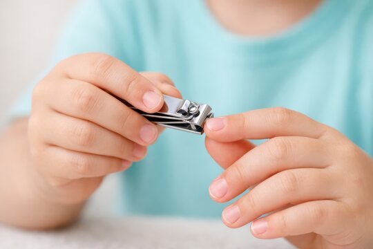 Caring for Little Hands: A child carefully trims a fingernail with a nail clipper, focusing on personal care.