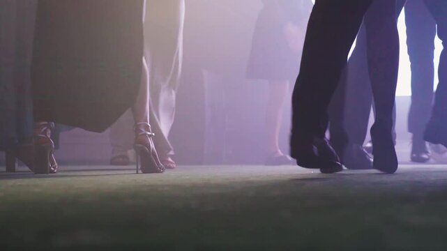 Chic models stride stylishly. Fashionable figures move elegantly across stage. Refined models showcase their fashionable attire during enchanting dance performance with warm lighting