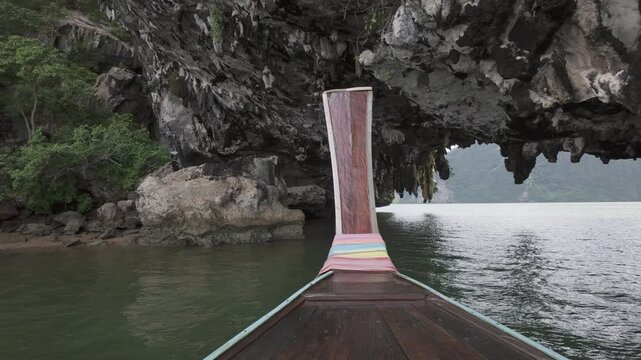 Traditional Wooden Longtail Boat Sailing Towards Massive Limestone Karst Cave In Tropical Ocean Waters