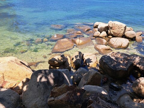Bright coastal landscape at Hon Chong, Nha Trang, Vietnam, featuring rock formations, clear blue water, and a sunny sky.