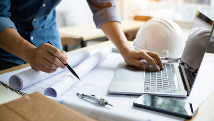 Engineer working with blueprints and laptop on construction project planning