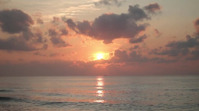 orange sky peaceful nature, travel destination, relaxation, scenic landscape, and serene morning atmosphere. Beautiful sunrise over calm ocean with golden light reflecting on water and dramatic clouds
