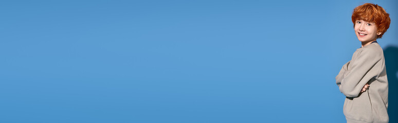 Stylish boy poses confidently in a vibrant blue background showcasing modern fashion trends