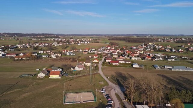 Ptuj, Slovenia&rsquo;s town center with urban streets, buildings, pedestrians, vehicles, and surrounding natural terrain is seen from a high-angle drone view on a clear winter day.
