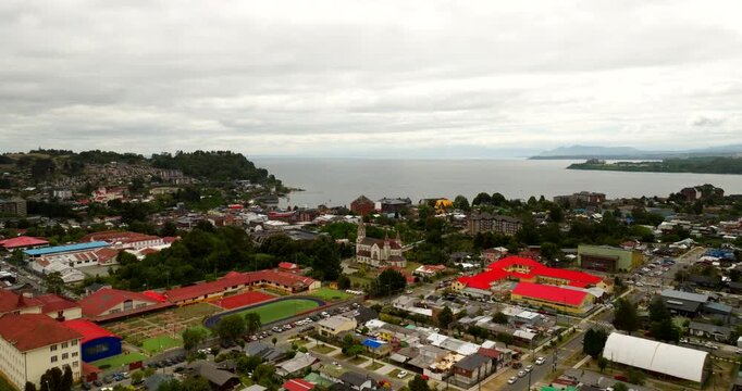 Puerto Varas on Lake Llanquihue in Los Lagos, Chile, showing waterfront neighborhoods and bay scenery beneath an overcast sky, cinematic aerial view