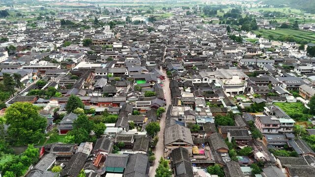 High angle aerial shot of traditional dark tiled roofs in Baisha ancient town, showing the dense architecture and historic layout of this Chinese cultural site.