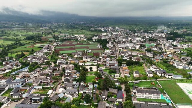 High angle aerial shot of Baisha ancient town and Fuguo monastery under misty mountains. Ideal for travel documentaries and Asian culture projects.