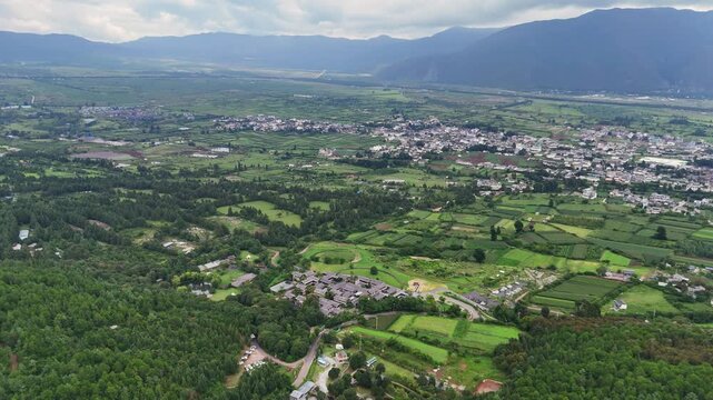 High angle aerial shot showcasing the sprawling landscape of Fuguo Monastery and the traditional Baisha town nestled against mountain ranges in Yunnan.