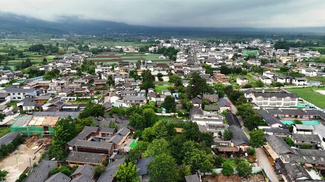 High angle aerial establishing shot of the historic Baisha village and surrounding Fuguo Monastery area under a cloudy sky in Lijiang, Yunnan.