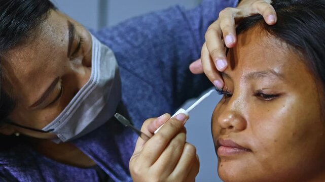 Professional make up artist applying false eyelashes and glue