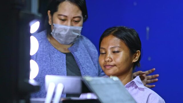 Asian makeup artist applying false eyelashes to a client