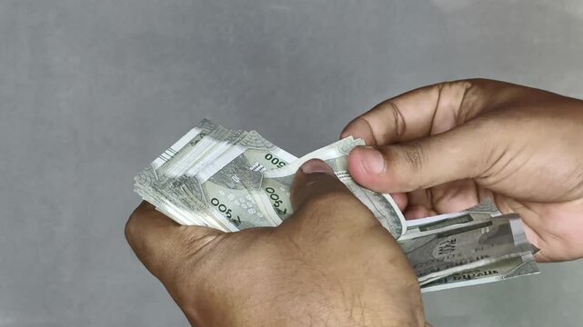 Indian five hundred rupee currency notes stack counting by hand. Extreme closeup isolated on white background. Salary, profits, earnings, bonus, success, wealth, income or financial freedom concept.