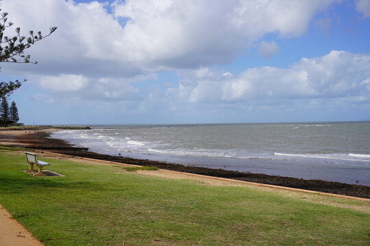 Beachfront park with ocean waves and bench at Redcliffe Queensland Australia coastal scene