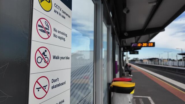 Safety and rule signage including no smoking, no vaping, and walk your bike notices on a railway station platform in Melbourne Australia. Commuter infrastructure and station regulations