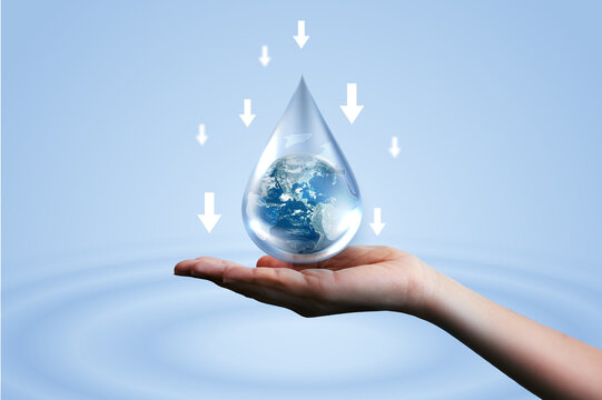 Hand holding water drop with Earth inside and downward arrows on blue ripple background. Concept of reducing water consumption, saving global resources, environmental conservation, and sustainability.
